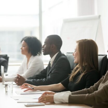 Diverse smiling businesspeople sitting at conference table